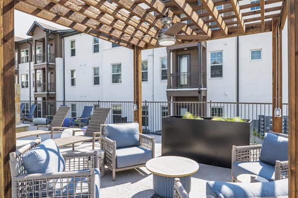 Outdoor pool and patio area at Birchway Hudson Oaks Apartments, featuring modern lounge chairs and lush landscaping