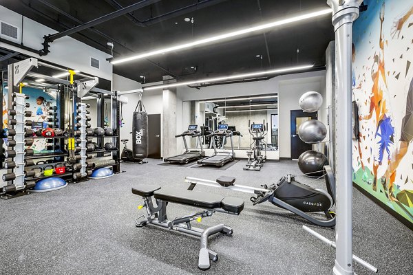 Fully-equipped fitness center at Ion Town Center Apartments with modern exercise machines and weights for residents' wellness