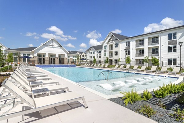 Olympic-size swimming pool at Espria Apartments with sun loungers and greenery Perfect for relaxation and social gatherings