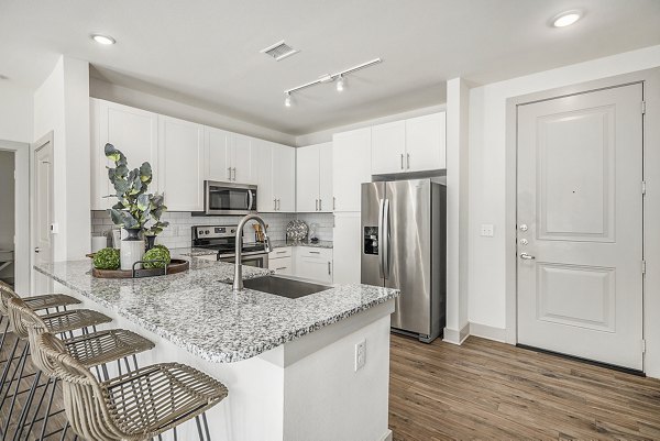 Modern kitchen with stainless steel appliances and granite countertops at Peak 83 luxury apartments