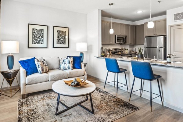 Cozy living room with modern furniture and large windows at Emerson at Red Oak Apartments, a luxury property by Greystar