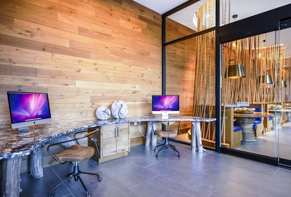 Modern business center with workstations at The Sur Apartments clubhouse, offering a professional workspace for residents