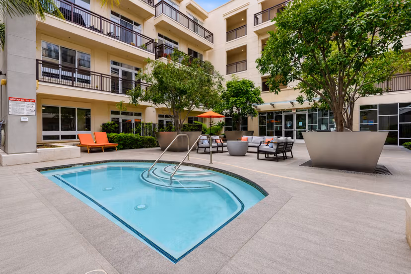 Outdoor courtyard with a small pool and lounge chairs surrounded by potted plants and seating areas at luxury apartments