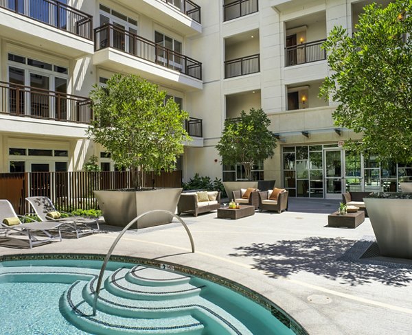 Outdoor courtyard with a small pool and lounge chairs surrounded by potted plants and seating areas at luxury apartments
