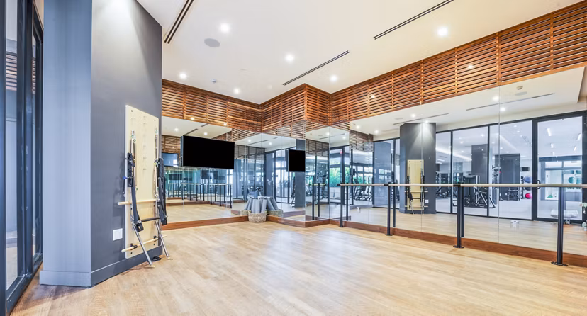 Yoga studio with mirrored walls and wooden floors at Crest at Pinecrest Apartments Ideal for residents seeking a serene fitness space