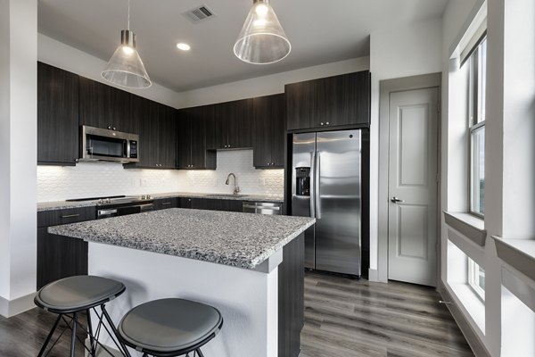 Modern kitchen with sleek countertops and stainless steel appliances at Alexan Braker Pointe Apartments