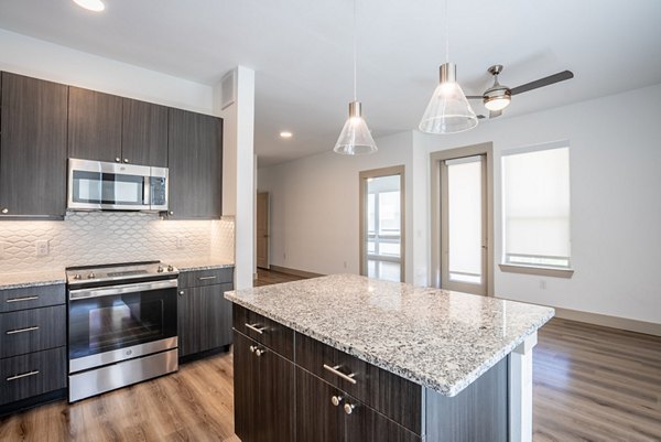 Modern kitchen with stainless steel appliances and granite countertops at Alexan Braker Pointe luxury apartments