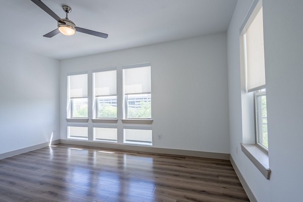 Modern living room with chic furnishings at Alexan Braker Pointe Apartments, featuring large windows and an open layout