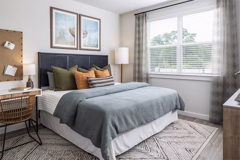 Cozy bedroom featuring a comfortable bed, desk, and natural light from a window