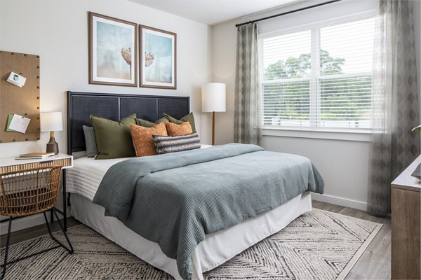 Cozy bedroom featuring a comfortable bed, desk, and natural light from a window