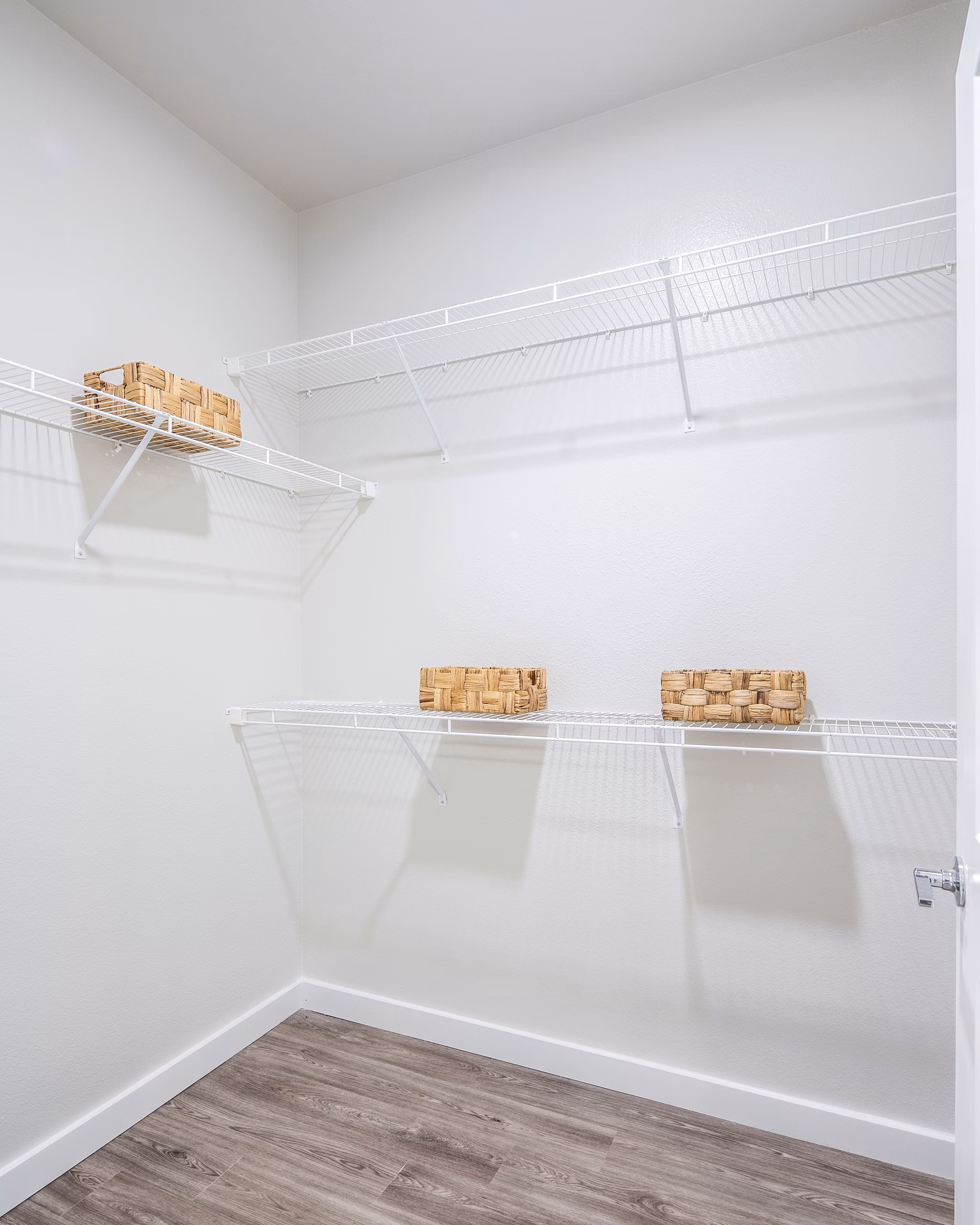 Empty closet with wire shelving and wicker baskets in luxury apartment