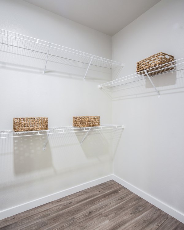 Empty closet with white wire shelving and woven baskets in luxury apartment