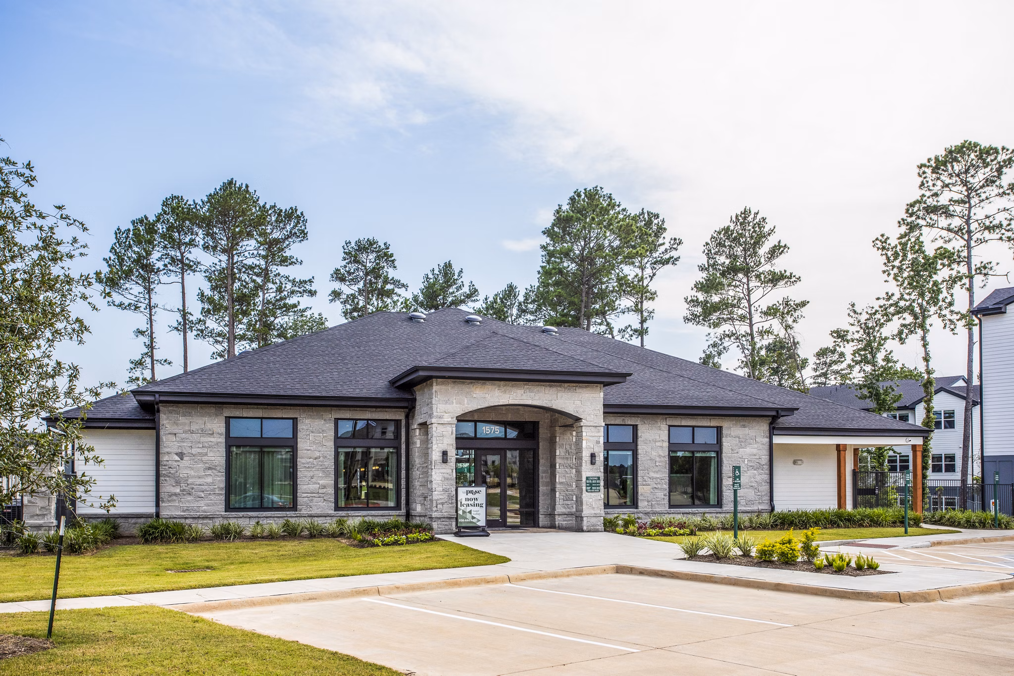 Modern single-story luxury apartments with a landscaped front area and parking lot in a vibrant neighborhood