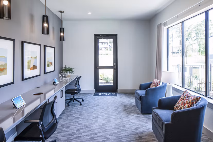 Modern office space with desks, chairs, and wall art featuring large windows in luxury apartments
