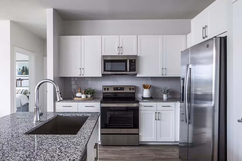 Modern kitchen featuring white cabinets and stainless steel appliances with a granite countertop and sink