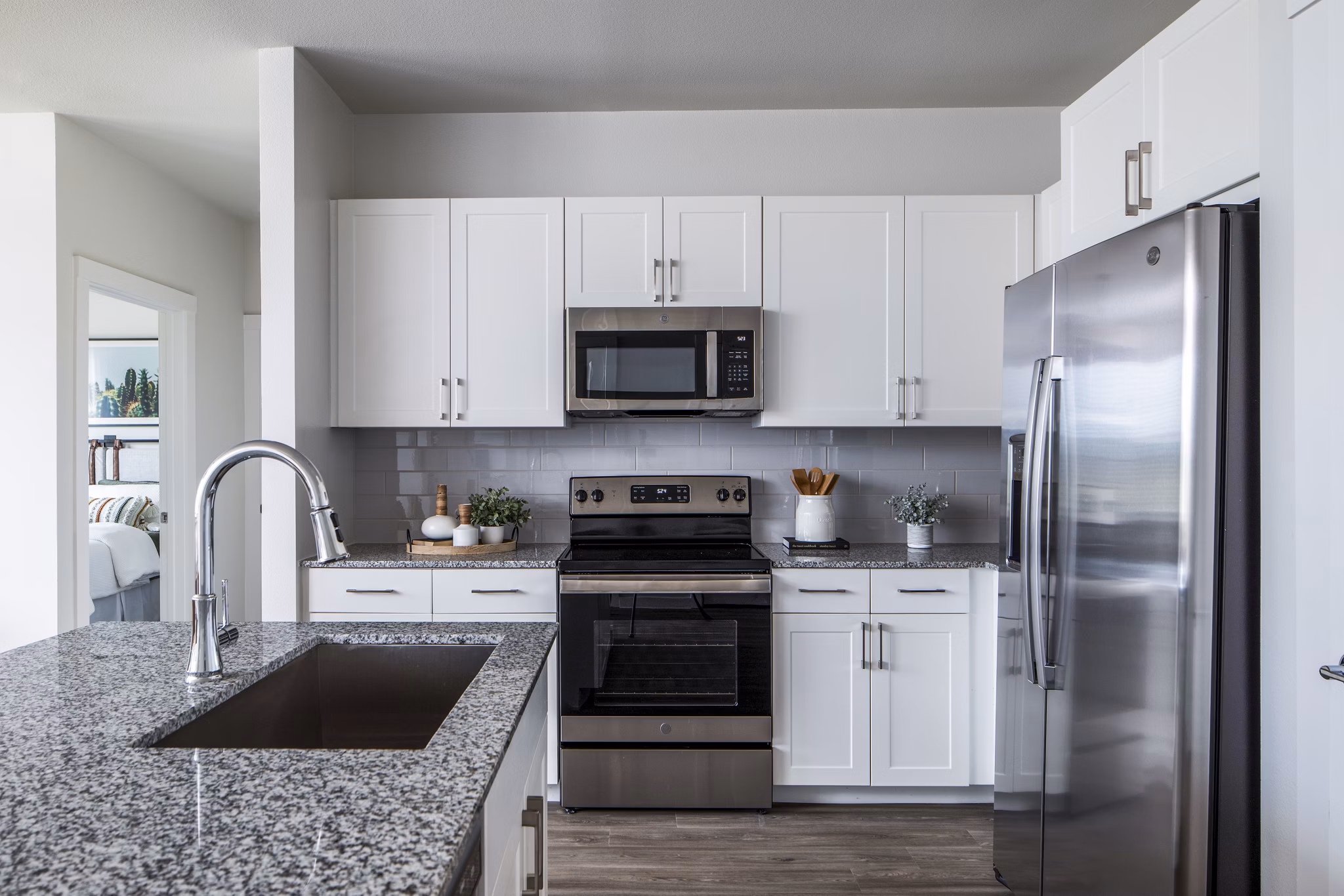 Modern kitchen featuring white cabinets and stainless steel appliances with a granite countertop and sink