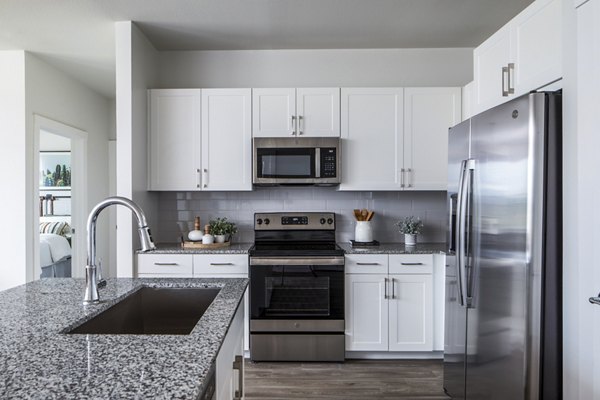 Modern kitchen featuring white cabinets and stainless steel appliances with a granite countertop and sink