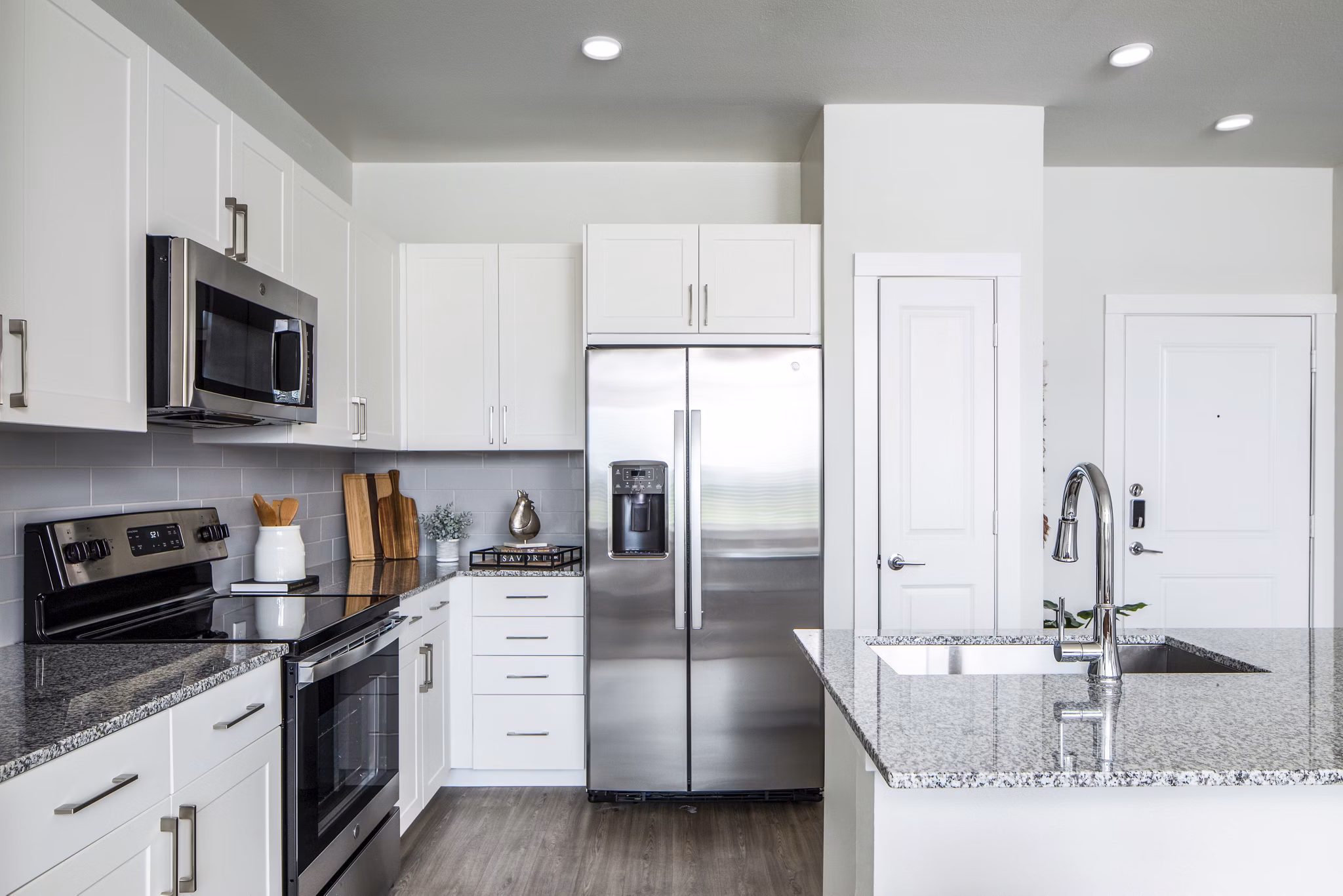 Modern kitchen with white cabinets and stainless steel appliances in luxury apartments
