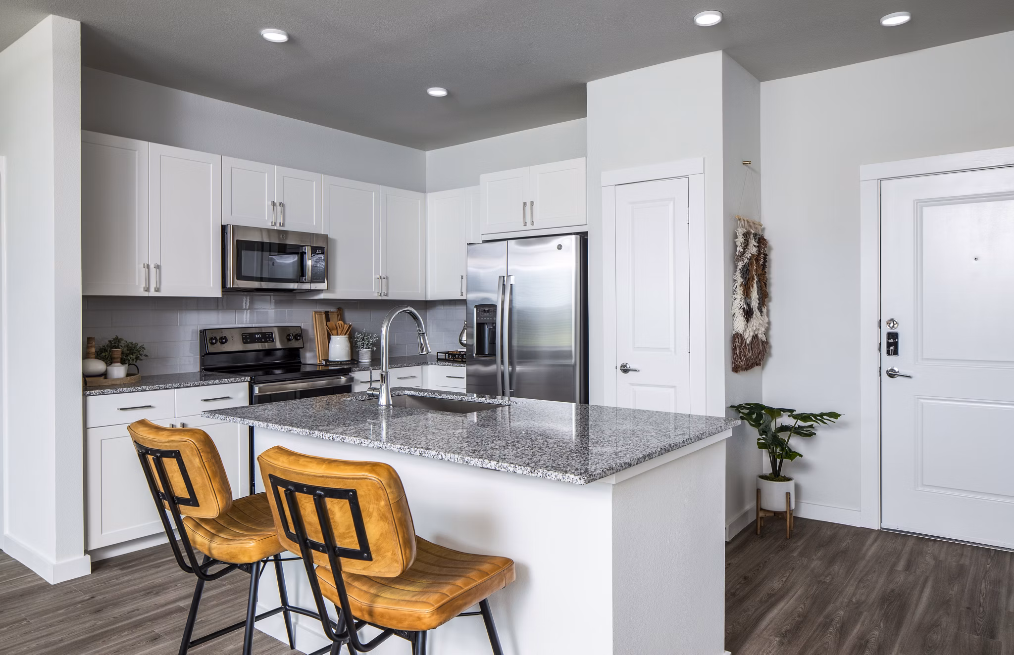 Modern kitchen featuring white cabinets and stainless steel appliances in luxury apartment