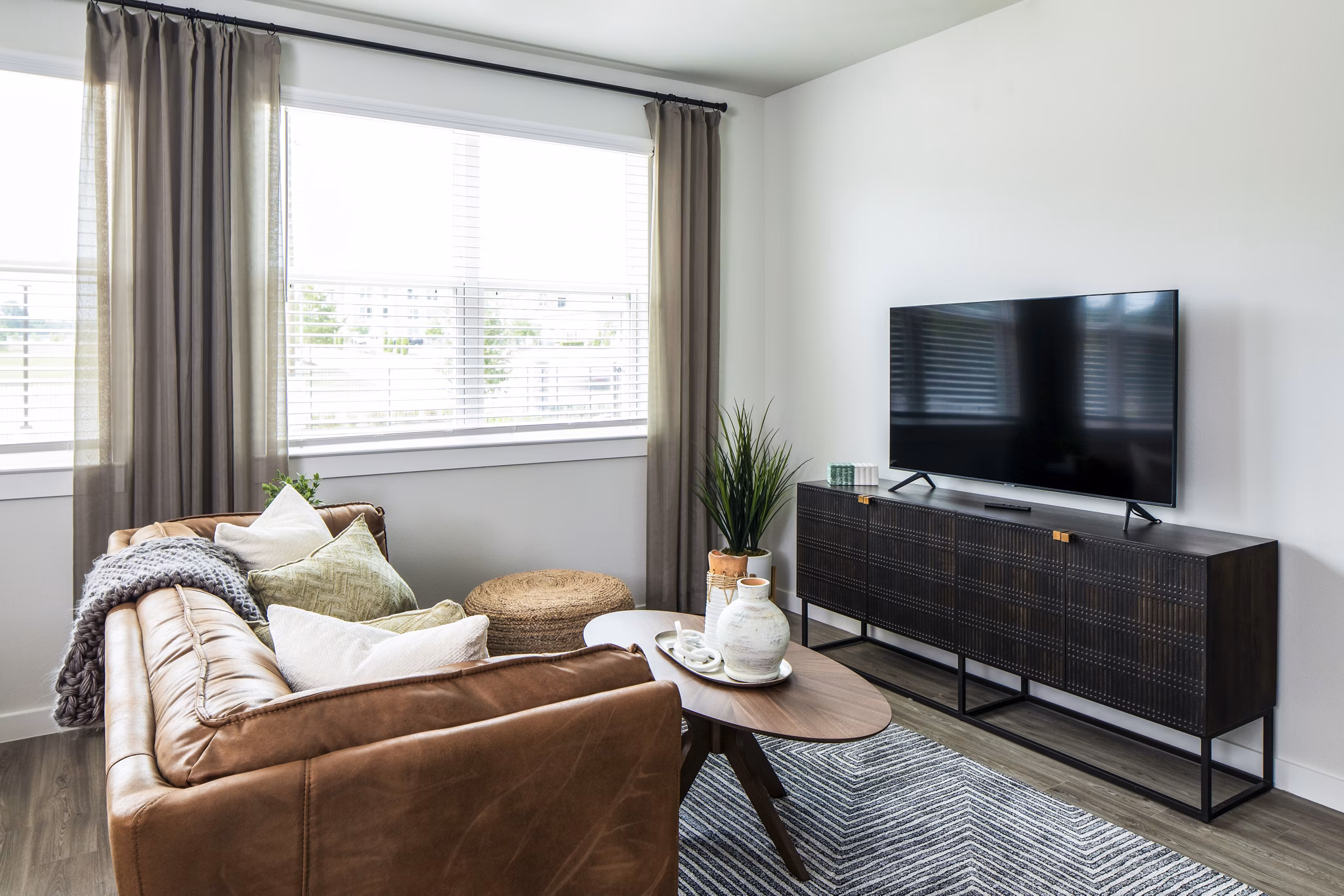 Modern living room featuring brown leather sofa and decorative plants in luxury apartment