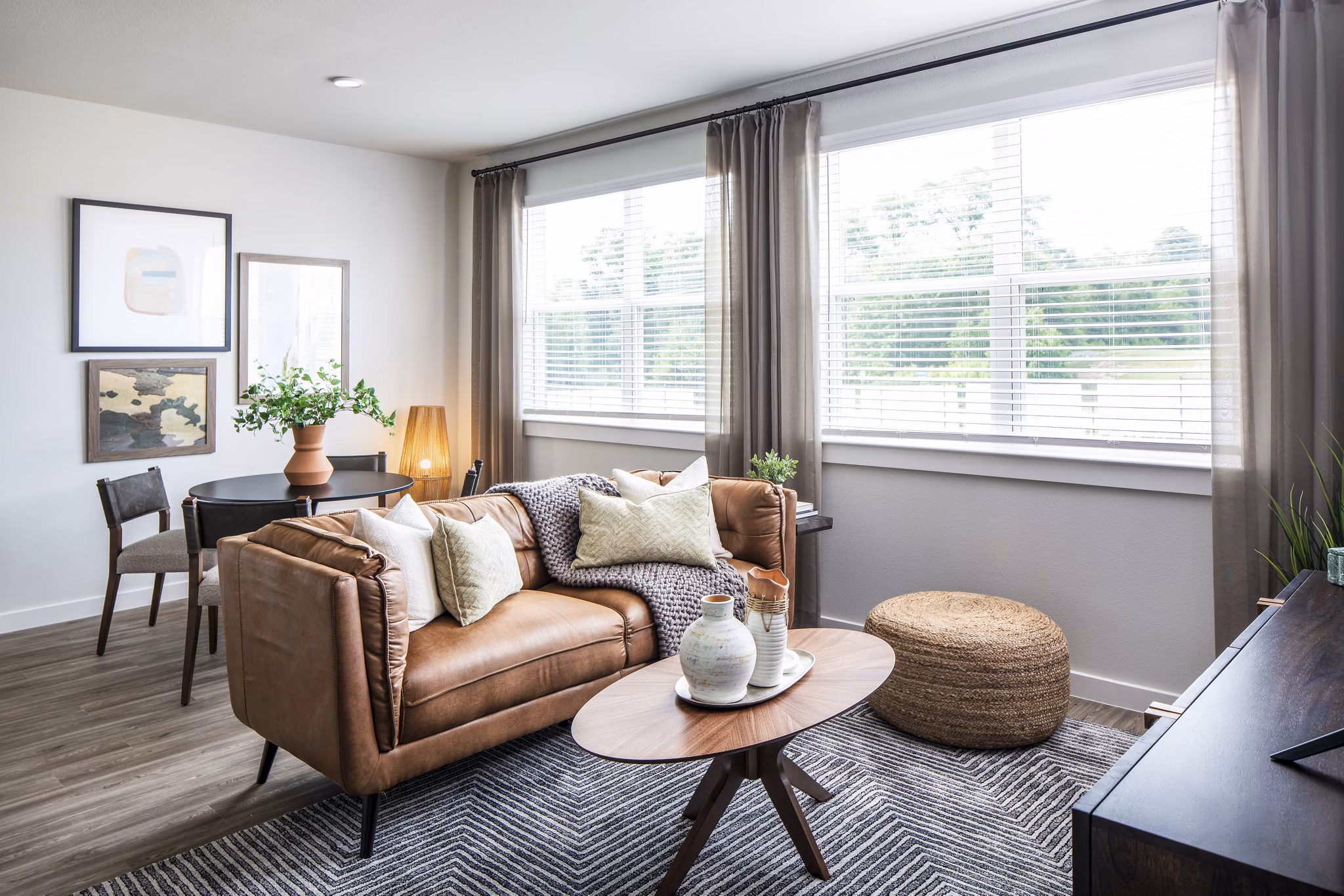 Modern living room with leather sofa, wooden coffee table, and large windows in luxury apartments
