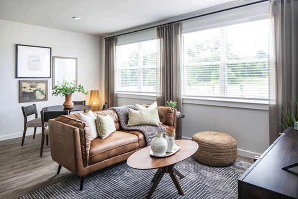 Modern living room with leather sofa, wooden coffee table, and large windows in luxury apartments