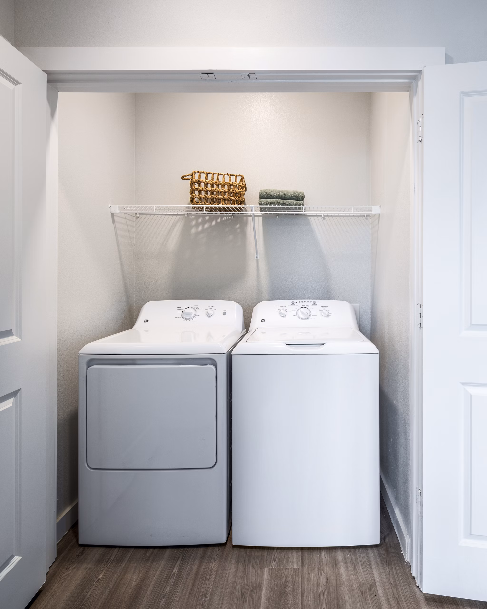 Laundry area featuring a washing machine and dryer with a shelf and basket in luxury apartments