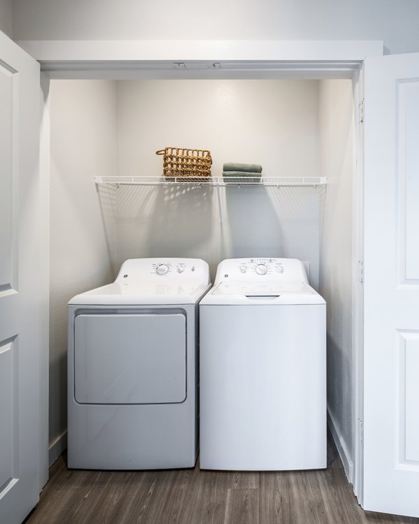 Laundry area featuring a washing machine and dryer with a shelf and basket in luxury apartments