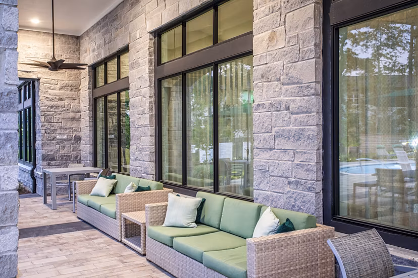 Elegant outdoor patio with wicker furniture and green cushions at luxury apartments