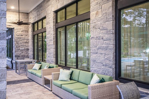 Elegant outdoor patio with wicker furniture and green cushions at luxury apartments