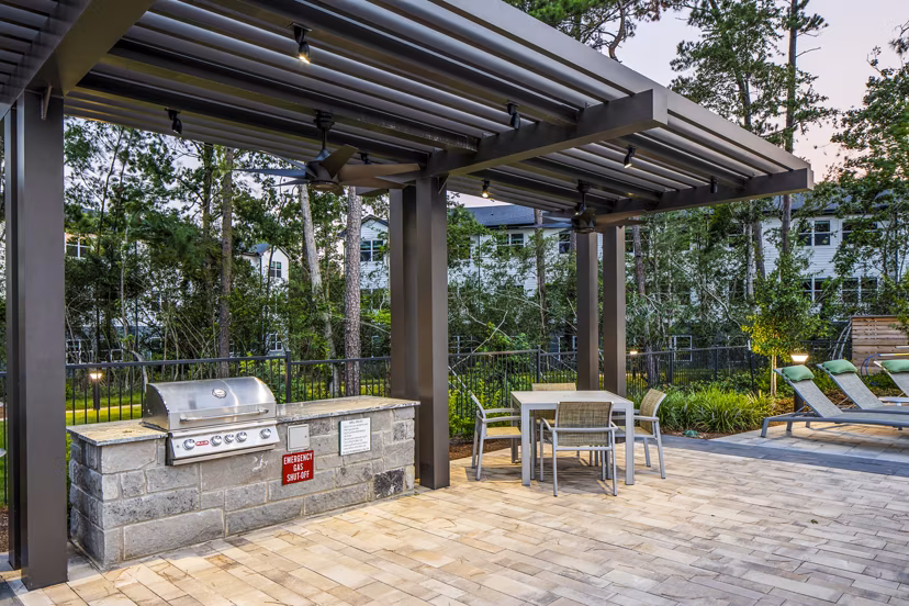 Outdoor patio area with a pergola, grill, and seating at luxury apartments