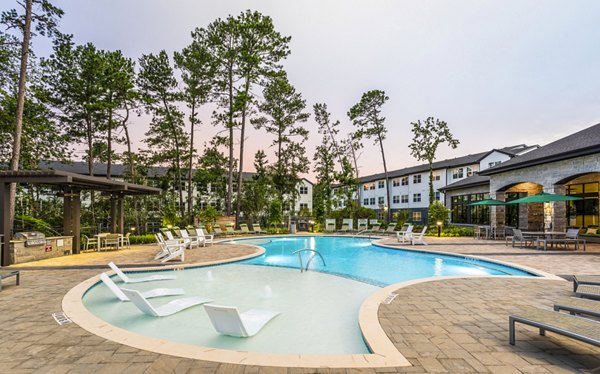 Outdoor swimming pool area with lounge chairs and lush landscaping at luxury apartments