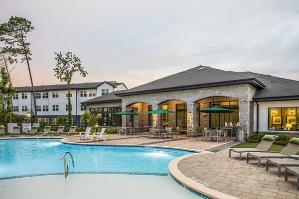 Resort-style swimming pool area with lounge chairs and modern apartments in the background