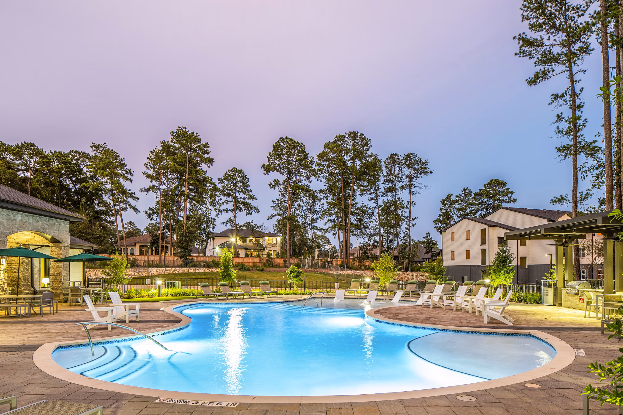 Outdoor swimming pool with lounge chairs and trees in luxury apartments community