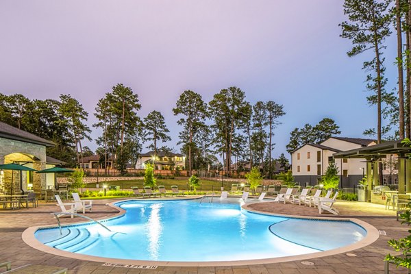 Outdoor swimming pool with lounge chairs and trees in luxury apartments community