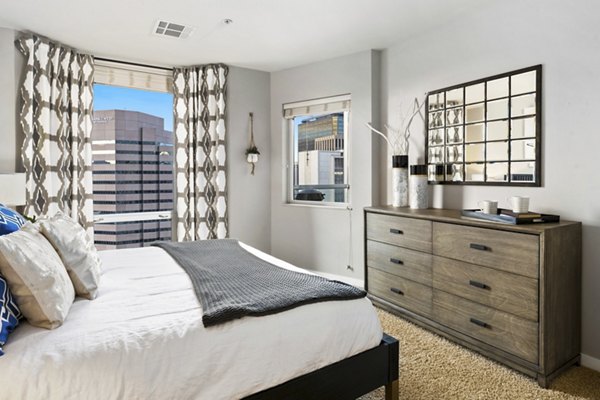 Cozy bedroom with city view at 1600 Glenarm Place Apartments, offering luxury living in a vibrant downtown setting