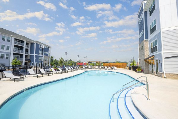 Resort-style pool with sun loungers at Indigo at Berewick Apartments, providing a luxurious outdoor retreat for residents