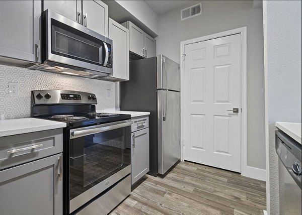 Modern kitchen with stainless steel appliances at Equinox on the Park Apartments, luxury living spaces in a vibrant community