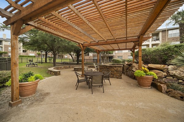 Serene patio with lush greenery at Equinox on the Park Apartments, perfect for outdoor relaxation and gatherings in a luxury setting