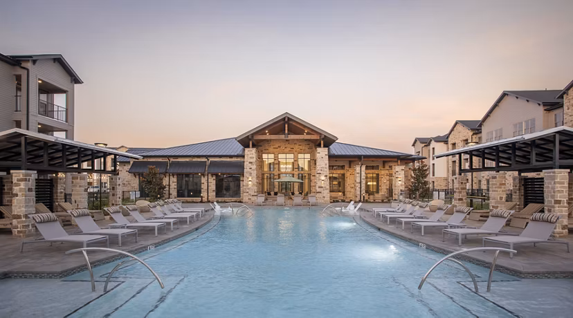 Resort-style pool at Broadstone Cross Creek Ranch Apartments featuring loungers and lush landscaping