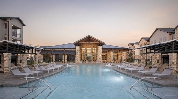 Resort-style pool at Broadstone Cross Creek Ranch Apartments featuring loungers and lush landscaping