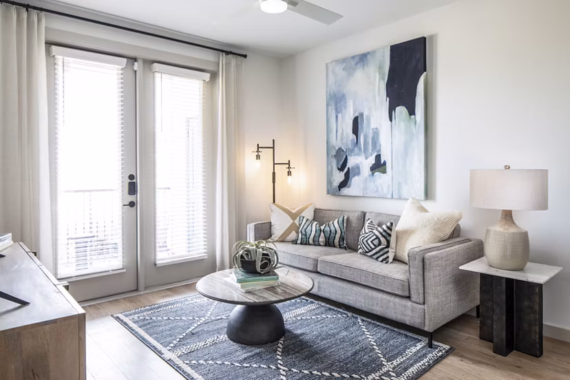 Modern living room with cozy seating and large windows at Broadstone Jordan Ranch Apartments