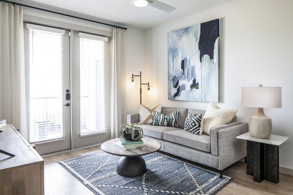 Modern living room with cozy seating and large windows at Broadstone Jordan Ranch Apartments