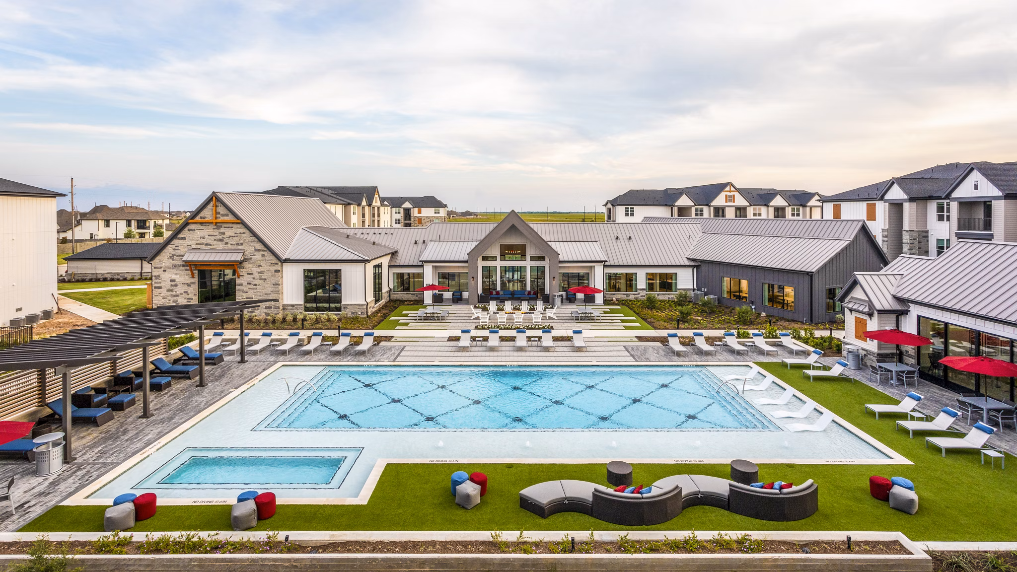 Luxury apartment complex featuring a large swimming pool and outdoor lounge areas in a vibrant community