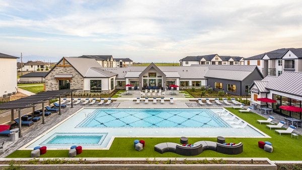 Luxury apartment complex featuring a large swimming pool and outdoor lounge areas in a vibrant community