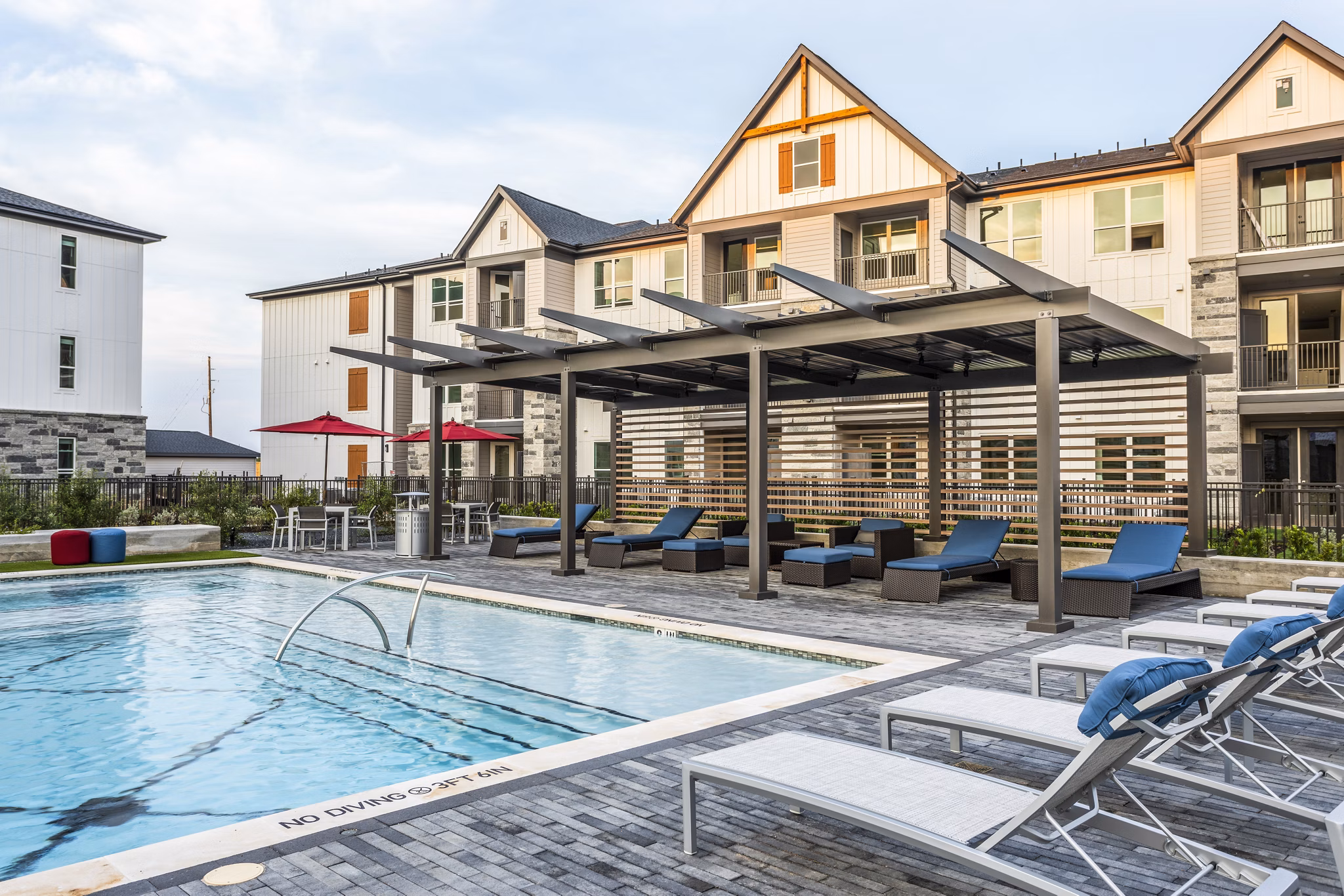 Outdoor swimming pool with lounge chairs and pergola in luxury apartments