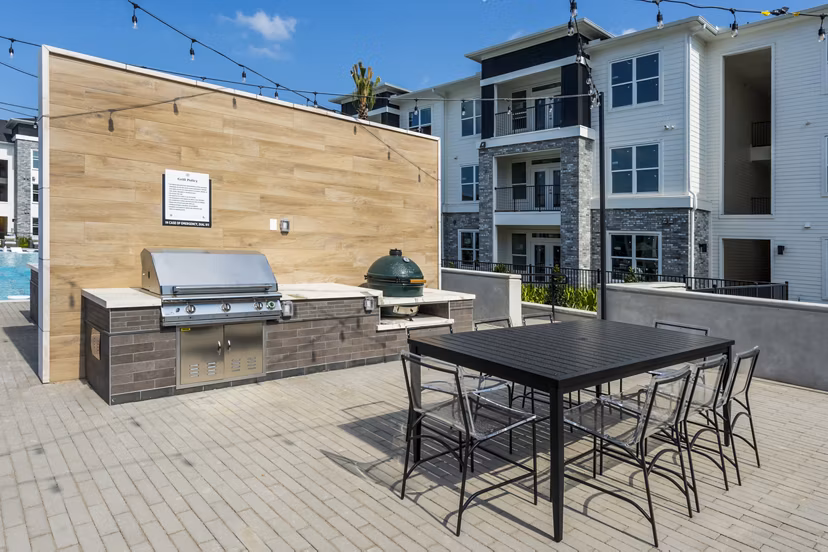 Outdoor grill area with seating at The Madison Apartments, offering modern amenities for luxury living