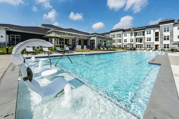 Modern outdoor pool at The Madison Apartments featuring luxurious seating and greenery