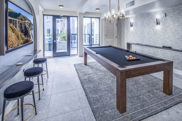 Clubhouse game room with pool table and lounge seating at Broadstone Claro Apartments