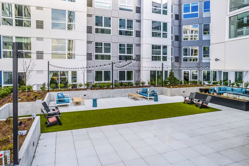 Patio with modern seating and lush greenery at Broadstone Claro Apartments